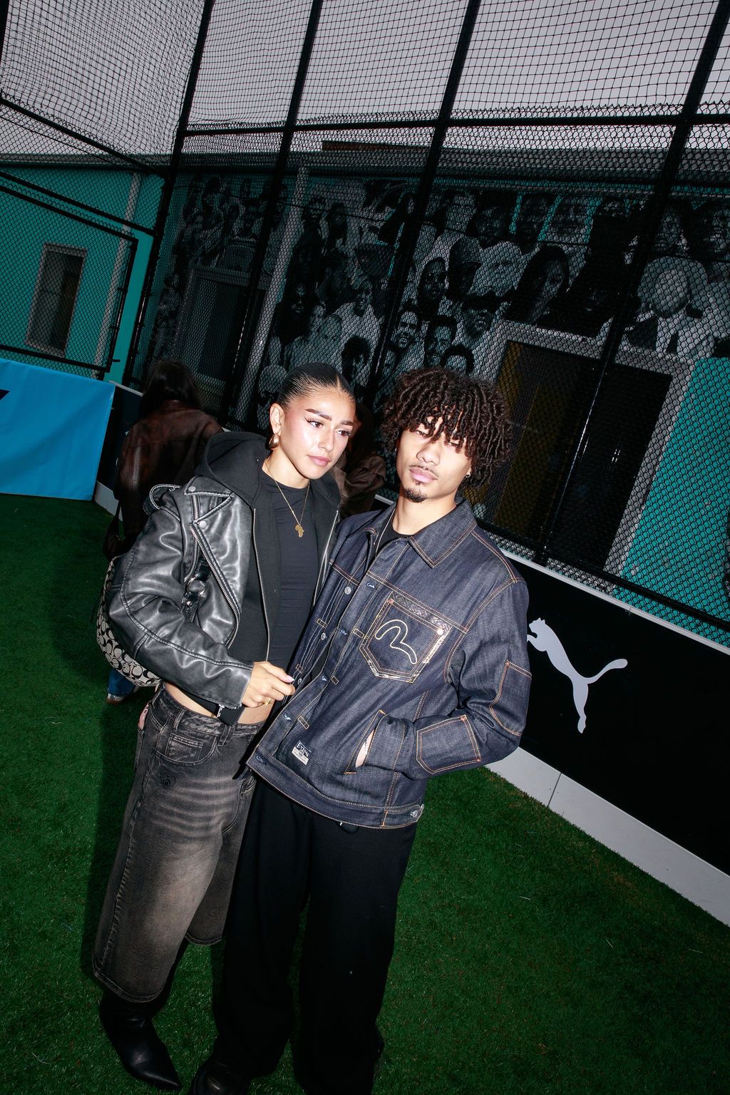 Two guests standing together near the indoor pitch