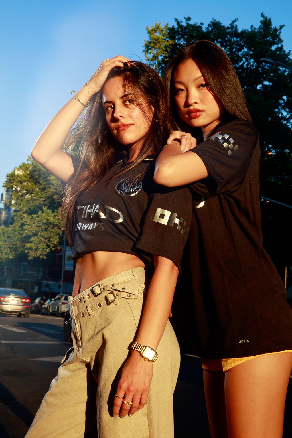Two models posing outdoors in black Manchester City shirts