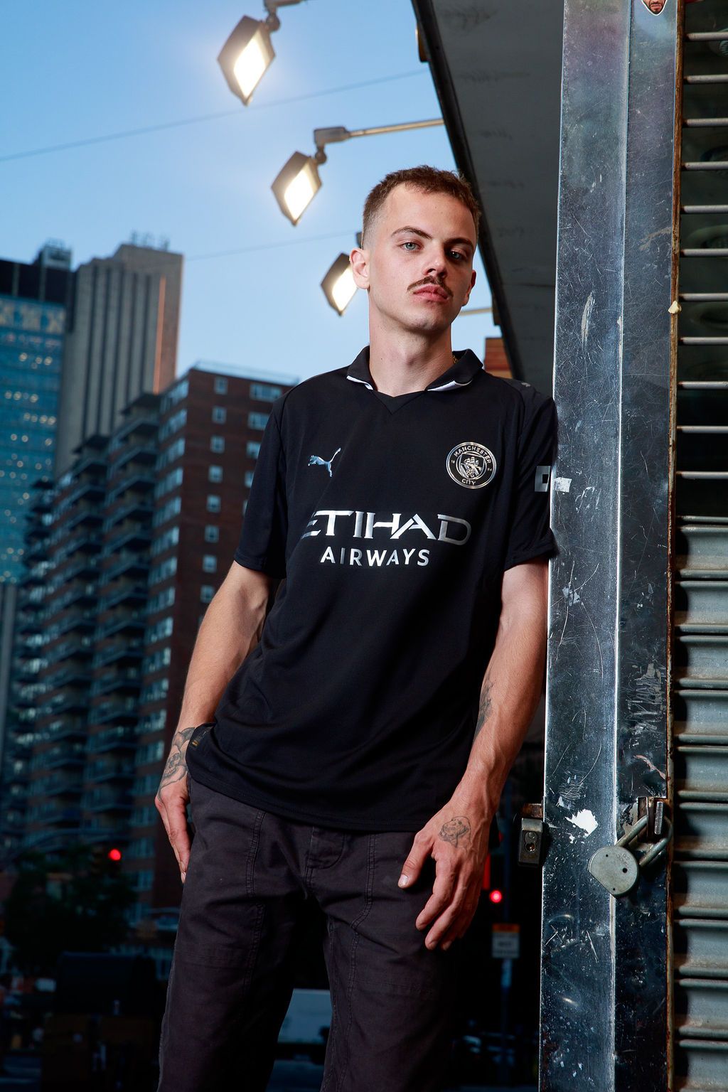 Model in a Manchester City away kit posing on a city street