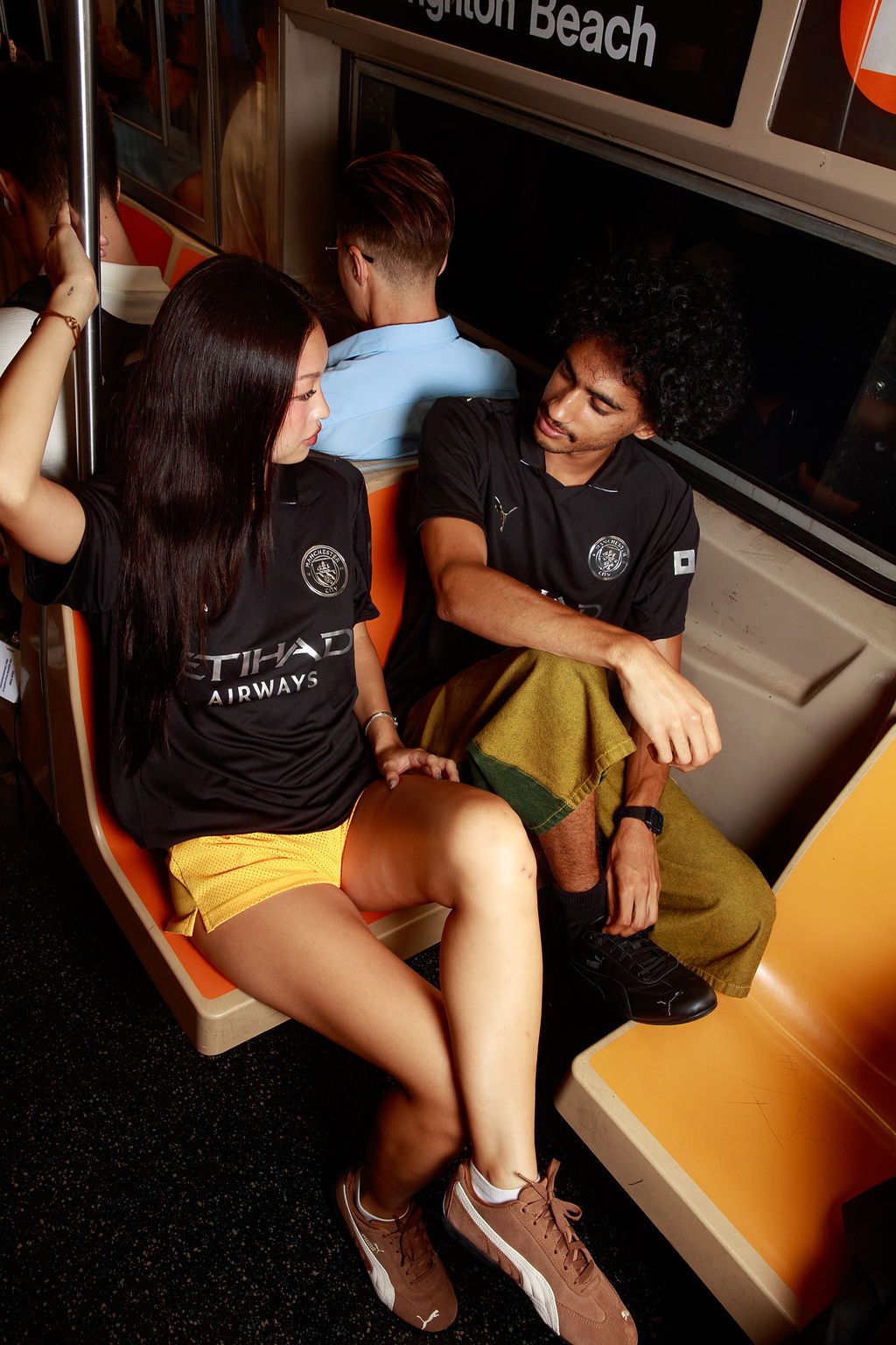 Models wearing black Manchester City away kits on a New York subway