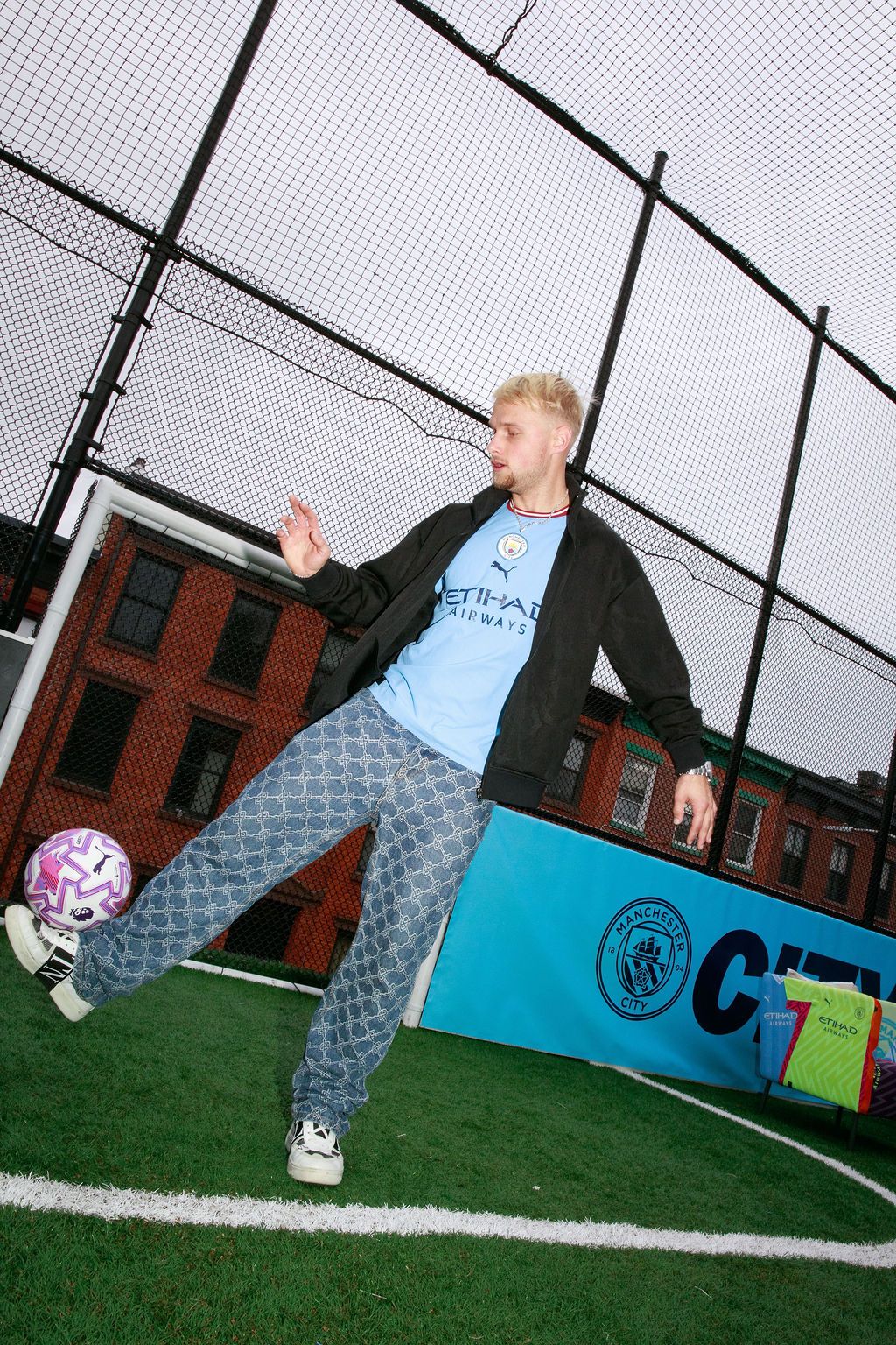 Guest posing with a football beside an indoor pitch