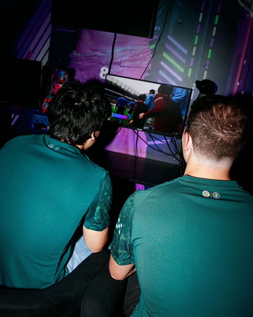 Players seen from behind gaming in Manchester City kits