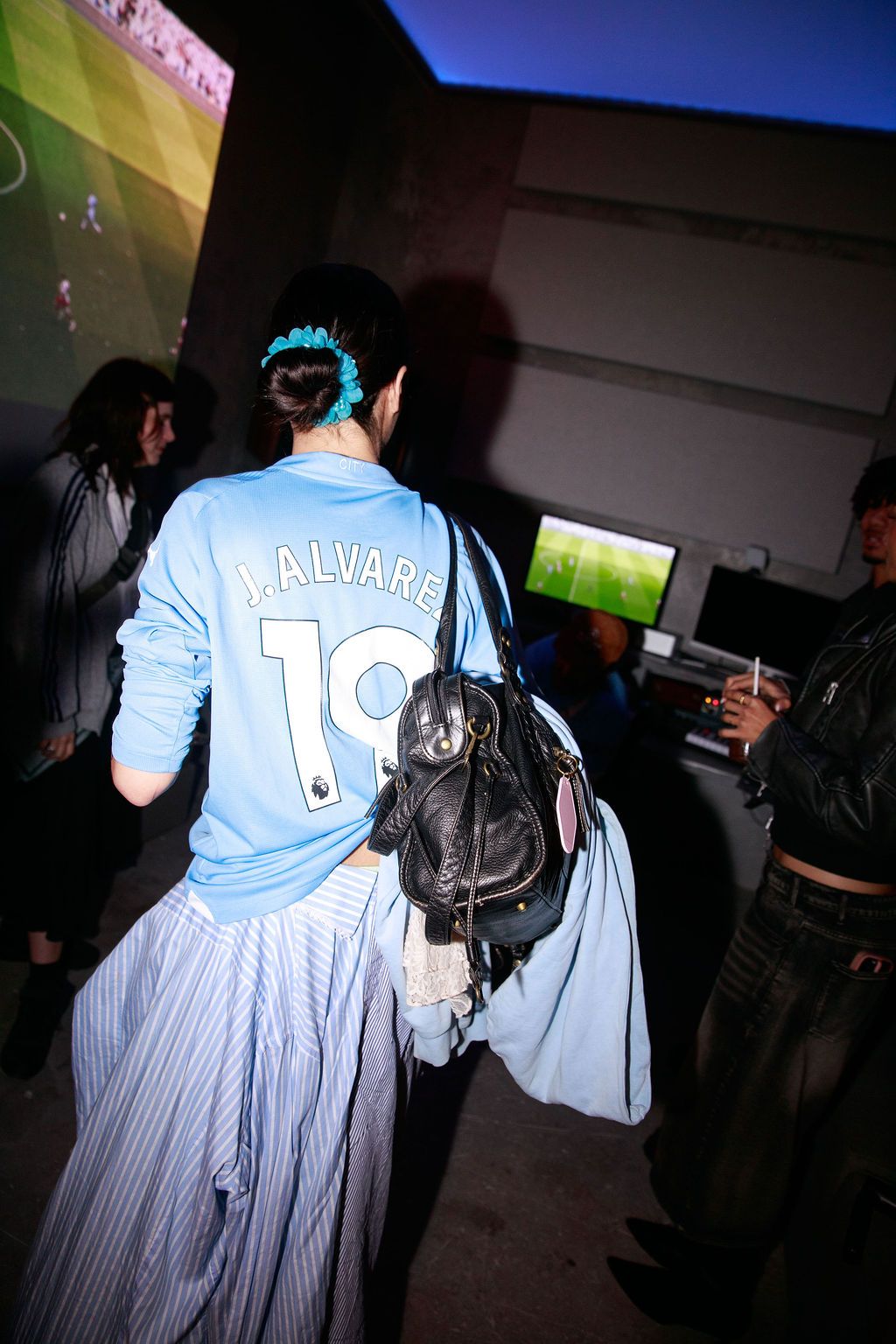Guests in Manchester City shirts gathering under blue light